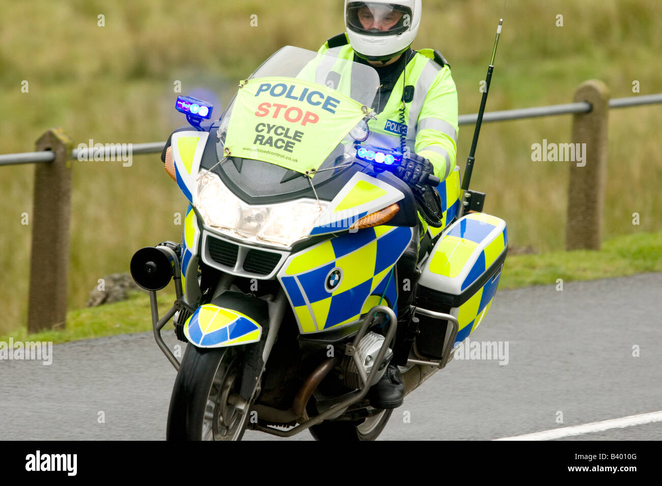 Motorbike traffic police motorcyclist with lights flashing escorting the Tour of Britain cycle race on rural road UK Stock Photo