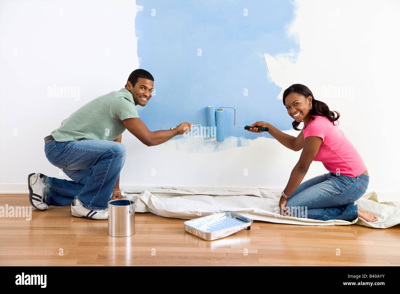Smiling African American male and female couple painting wall blue Stock Photo