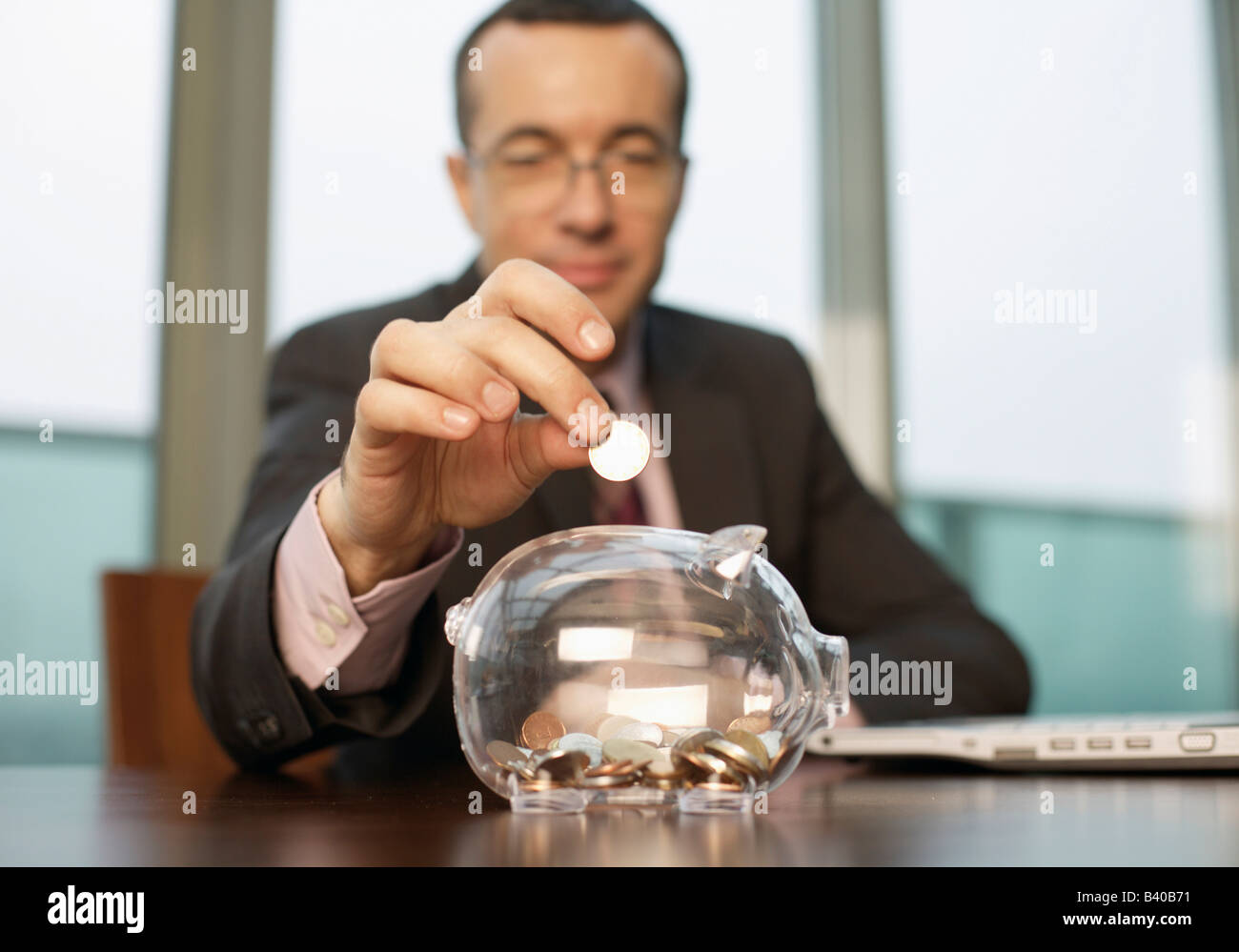 Businessman putting a coin in a piggy bank Stock Photo - Alamy