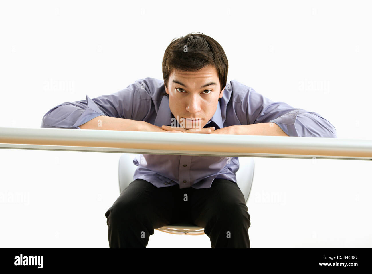 Young Asian business man with head on desk looking at viewer Stock Photo