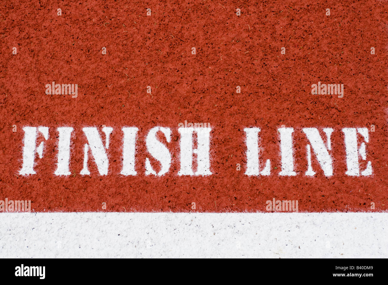 Closeup of white finish line words and lane on red running track Stock