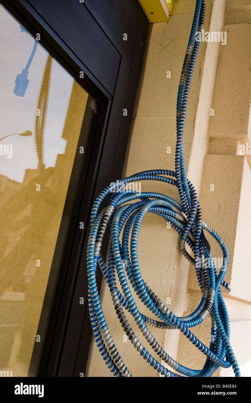 Coiled electrical cable hanging outside a building Stock Photo Alamy