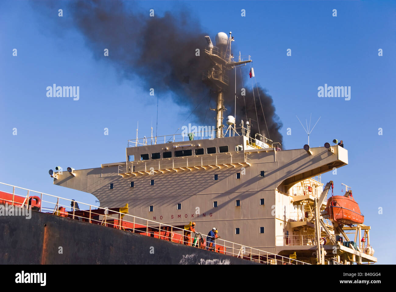 Black smoke rises from ship's funnel as the ship approaches the quay. Stock Photo