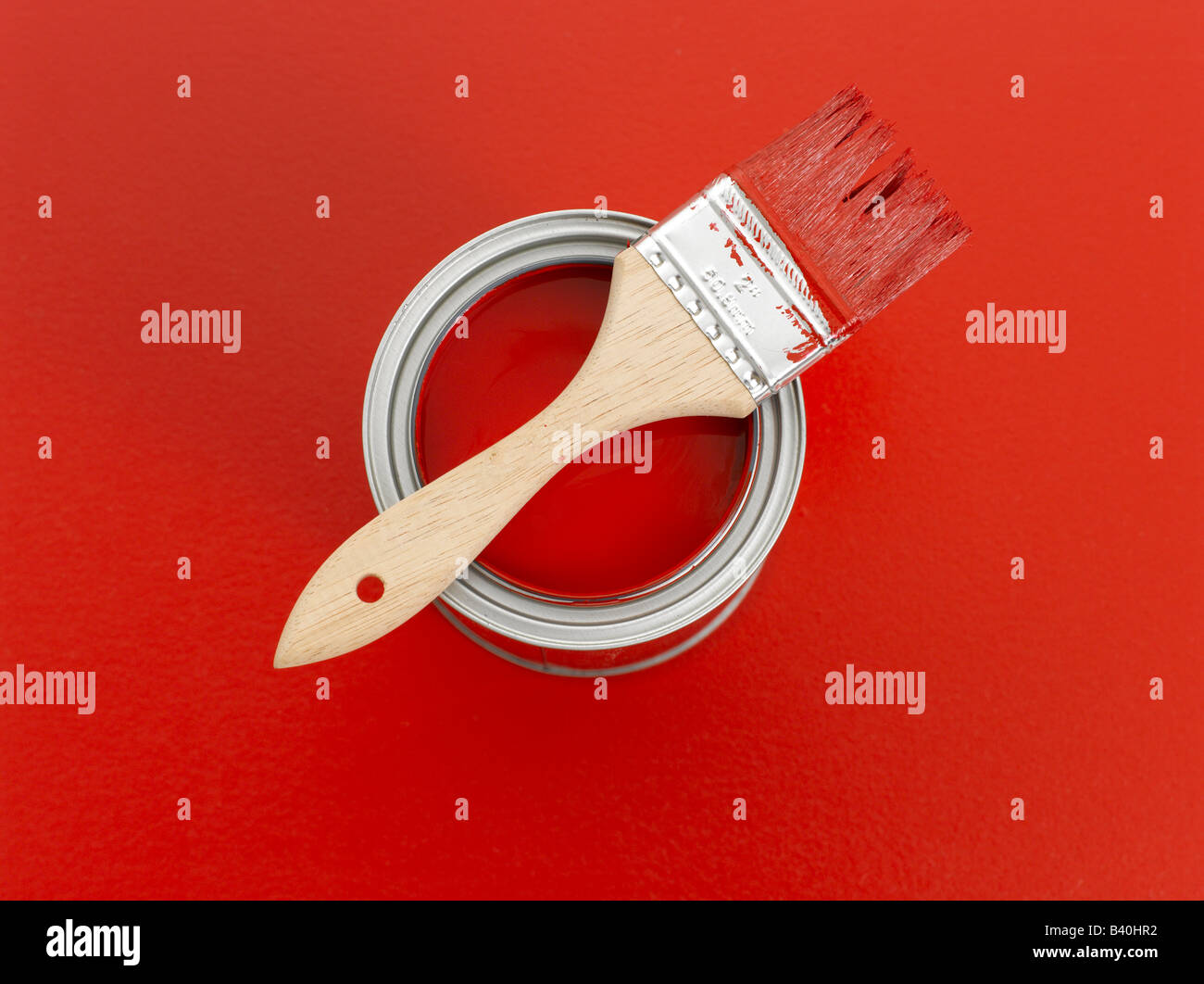 Can of red paint and paintbrush on red background Stock Photo