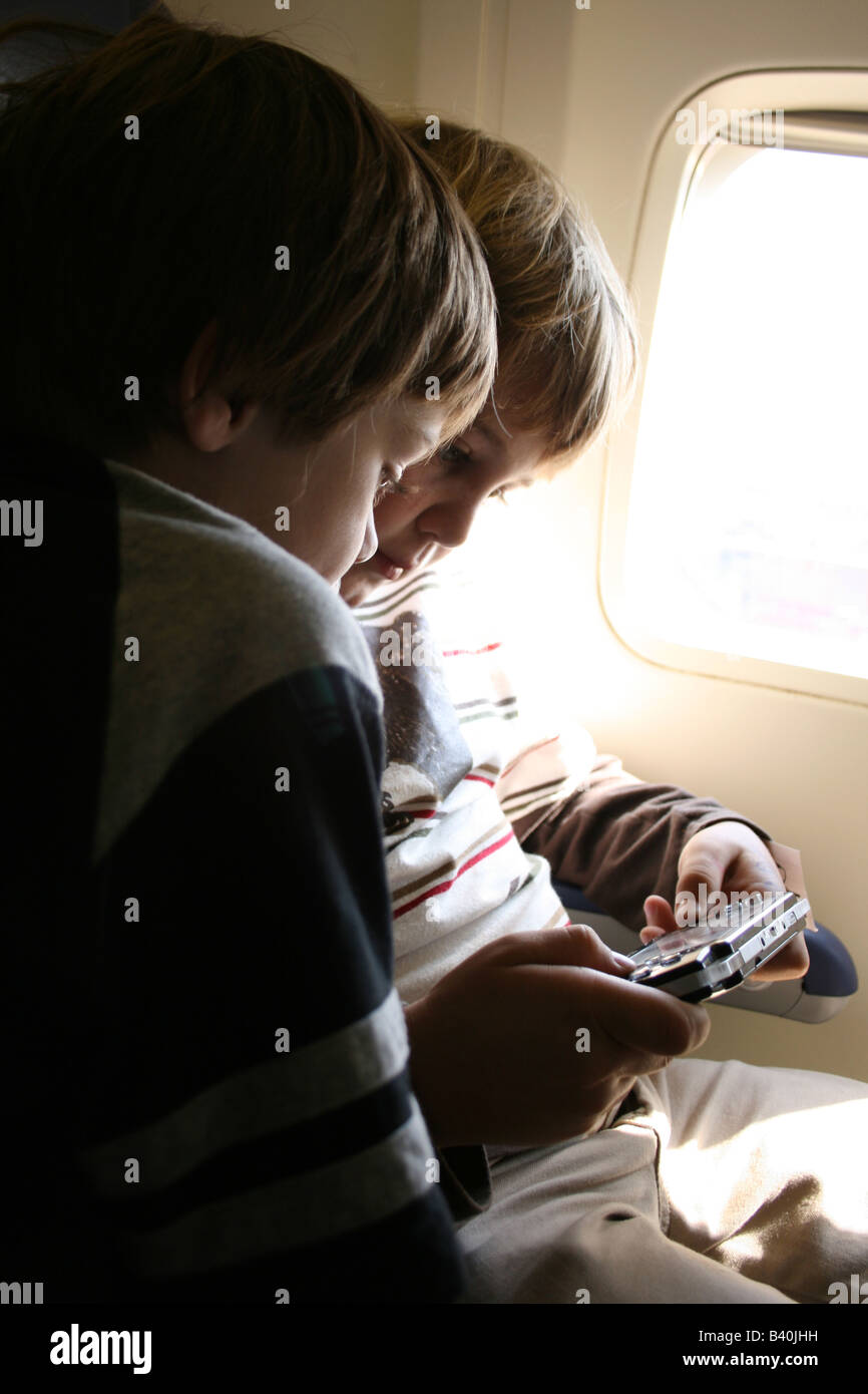 children playing play station portable psp game on an airplane Stock Photo