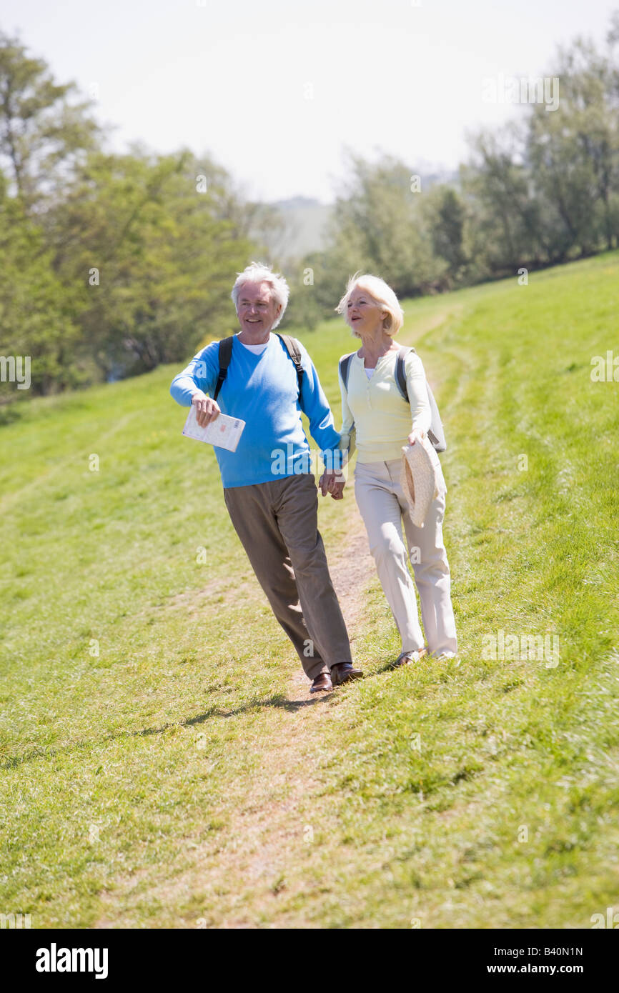 Couple walking on path in park holding hands and smiling Stock Photo ...