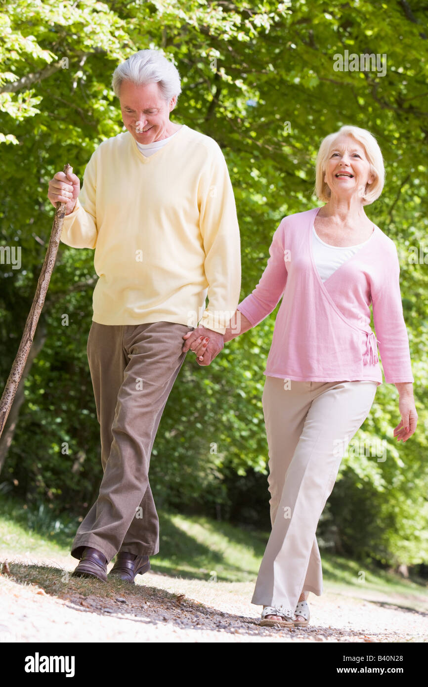 Couple walking on path in park holding hands and smiling Stock Photo ...