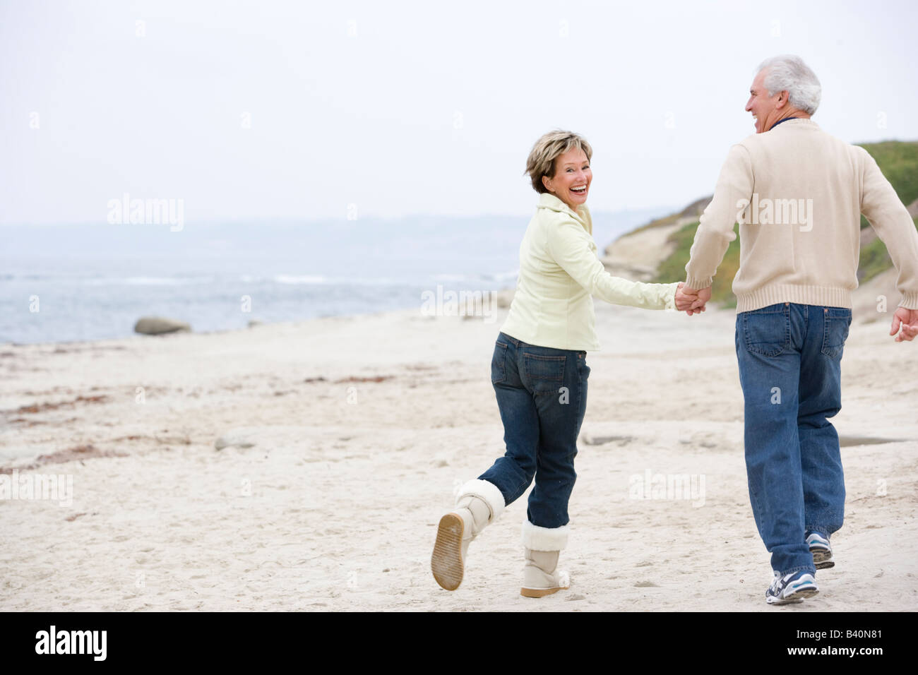 Couple at the beach holding hands and smiling Stock Photo - Alamy