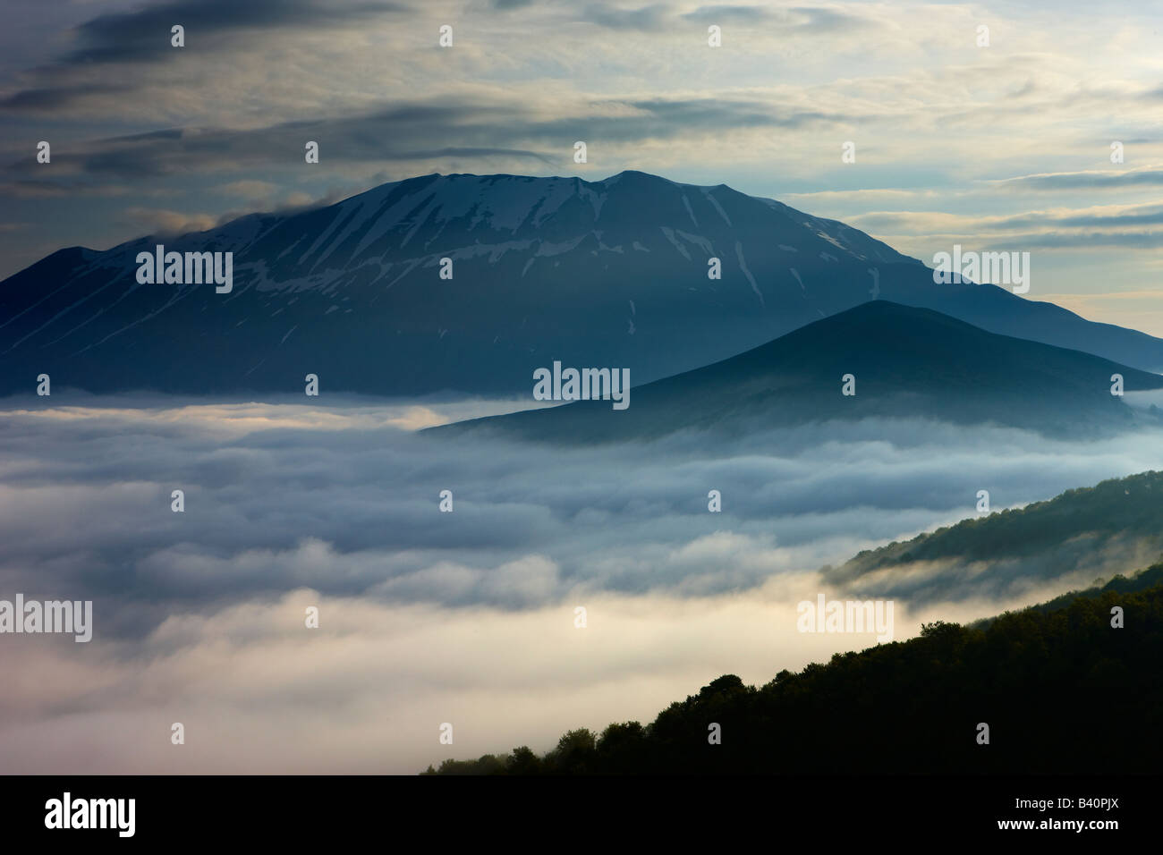 mist lying on the Piano Grande at dawn with the mountains of Monti Sibillini National Park rising above, Umbria, Italy Stock Photo