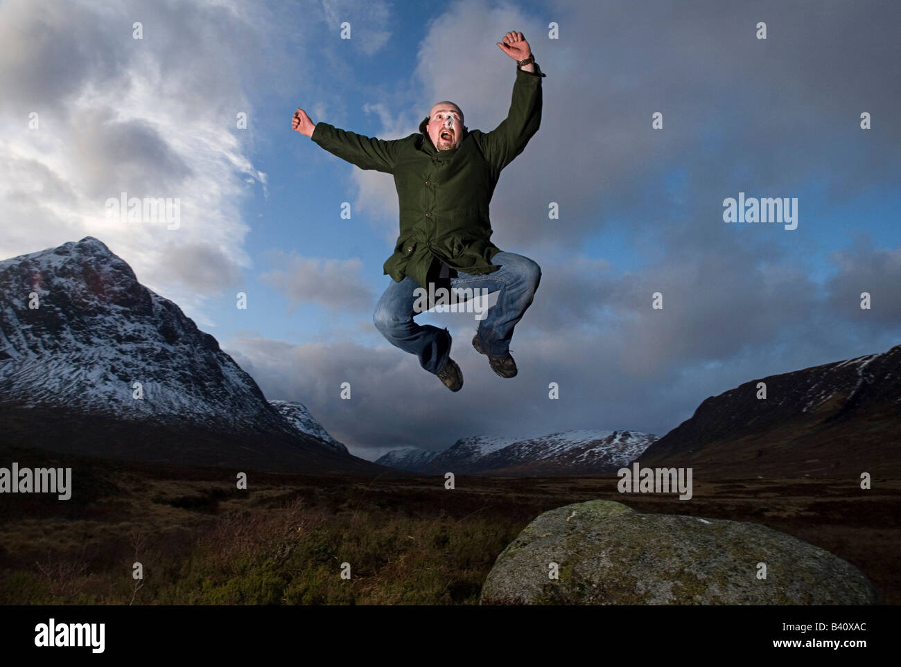 Man leaps for Joy under the mountain Buachaille Etive Mor in the Scottish Highlands while walking the West Highland way. Stock Photo