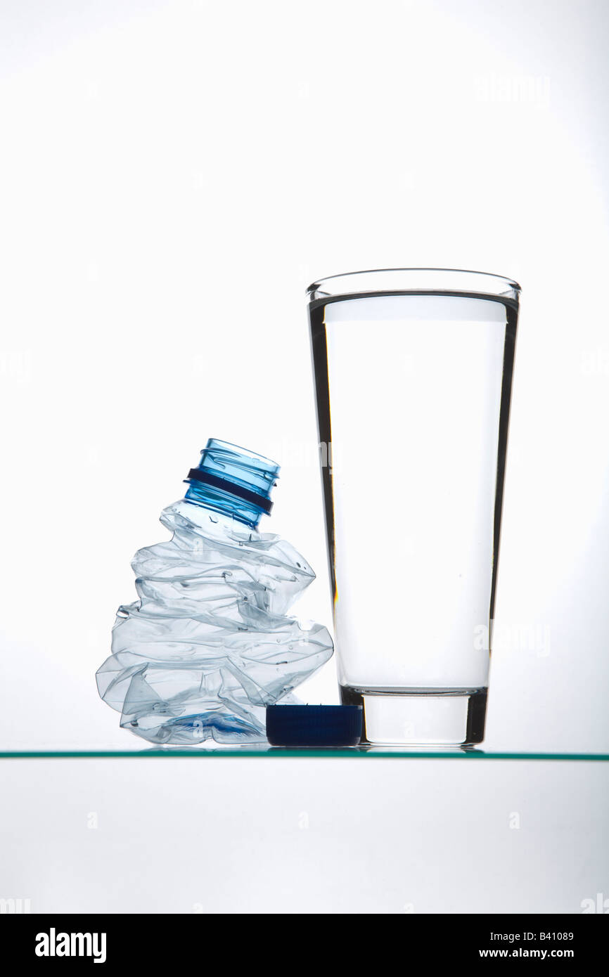 Filled drinking glass by a swatted plastic bottle Stock Photo