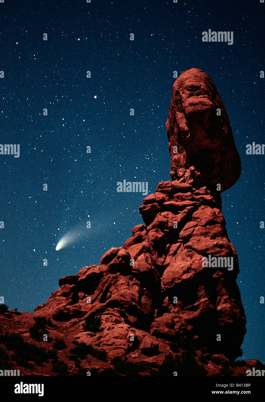 USA, Utah, Arches National Park. Comet Hale-Bopp streaks across the night sky past Balanced Rock, which is lit by a half-moon. Stock Photo