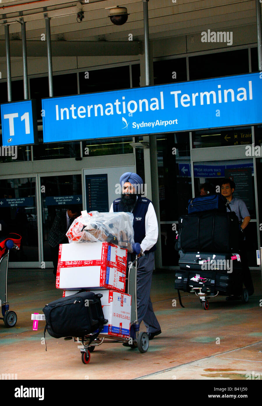 A Sihk Indian Taxi driver wheels a passengers luggage from the International Terminal at Sydney s Mascot airport Stock Photo