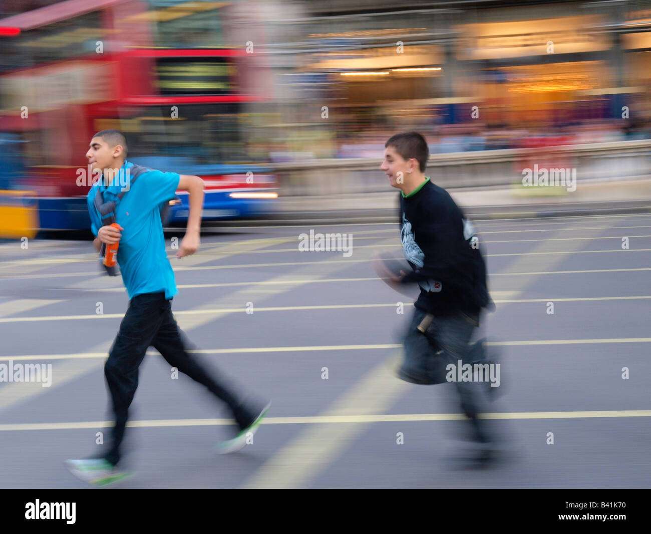 Boys chasing each other running across Oxford Circus London UK Stock Photo