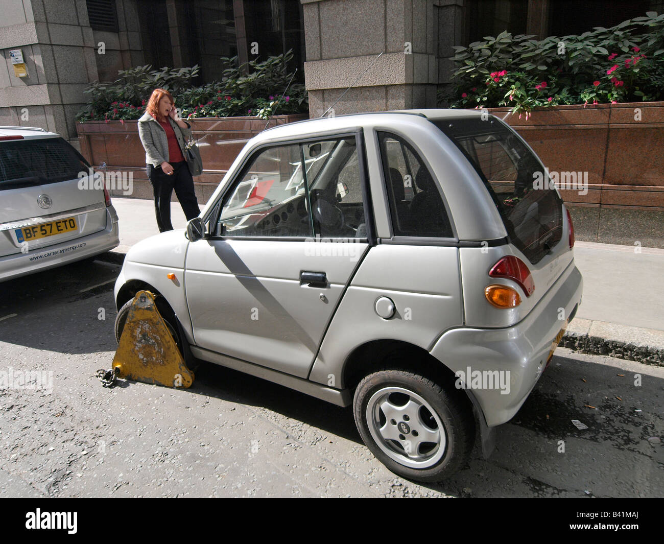 wrongly parked Reva G Wiz electric car with wheelclamp London UK Stock Photo
