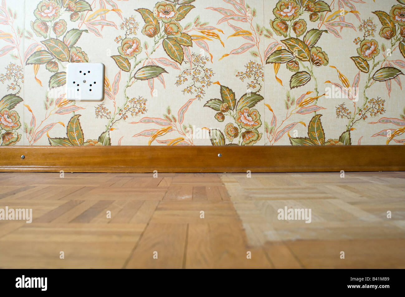 Electrical plug outlets on a vintage wallpaper of a wooden floored room