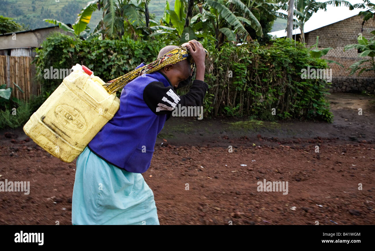 A young Rwandan girl carries water from the well, a strenuous job as ...