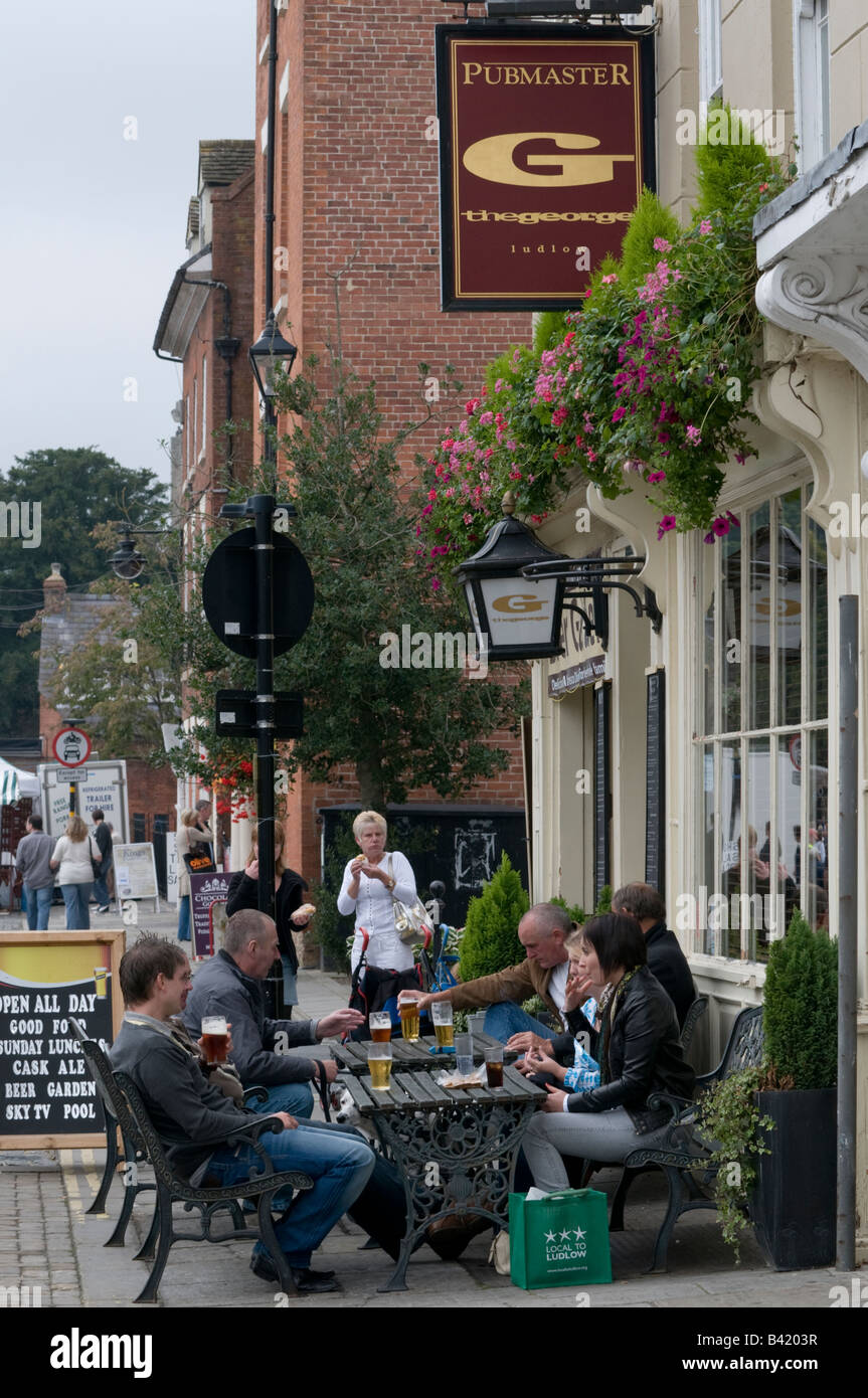 Group of people sitting outside The George pub drinking beer Ludlow Shropshire England Stock Photo