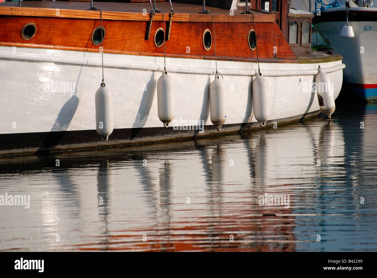 wooden boat with fenders reflecting in the water,norfolk broads Stock