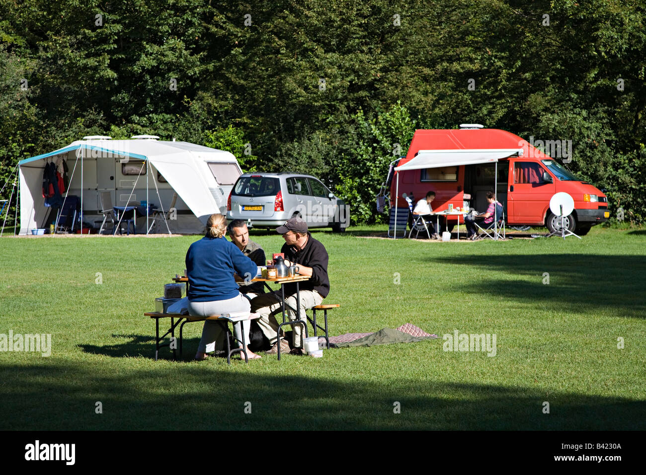 People relaxing and eating at table with caravans on campsite Netherlands Stock Photo