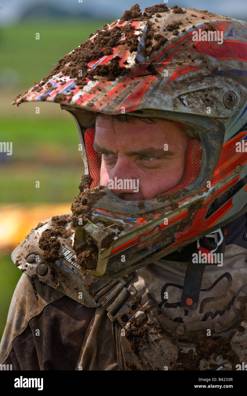 man with crash helmet involved in motocross racing with his helmet and clothing covered in mud