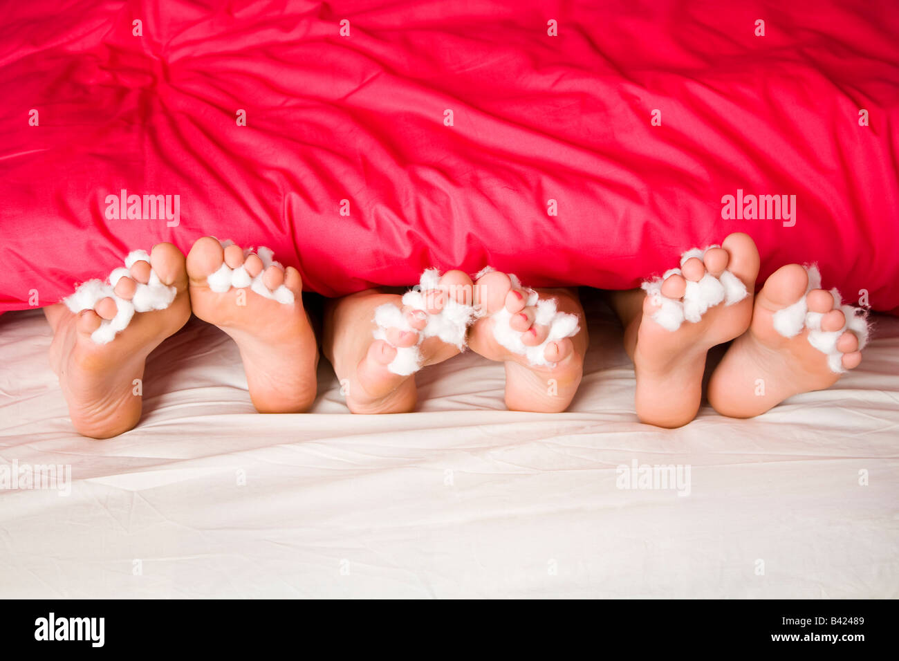 Bare feet sticking out from a quilt on a bed with cotton wool between