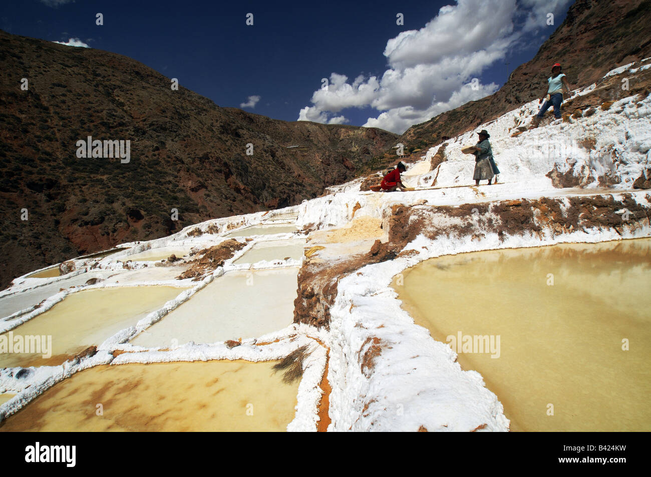 Women work extracting salt in the salt pools of Salineras de Mara near Cuzco, Peru Stock Photo