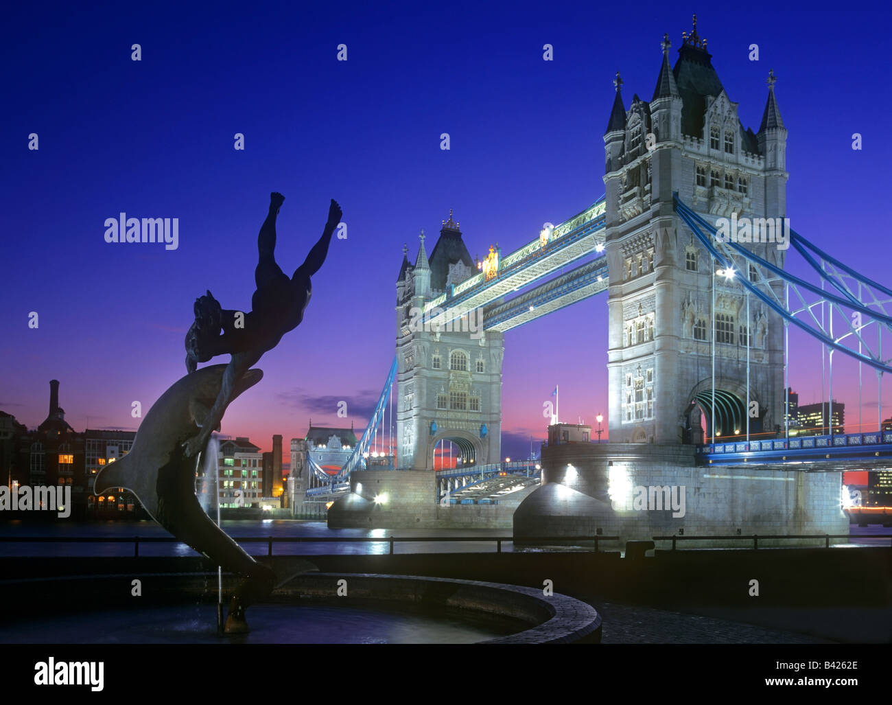 Tower Bridge Night Landscape City River Thames London lit up at night with statue of girl and dolphin fountain in foreground,City of London England UK Stock Photo