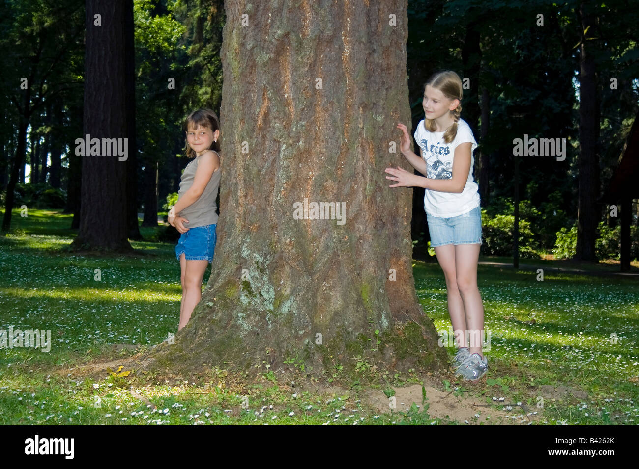 Two young girls playing hide and seek in a forest area Stock Photo