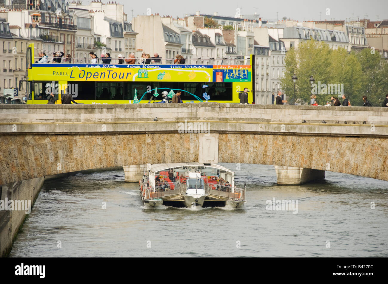 tourist boat on the river Seine with open top tour bus crossing bridge ...