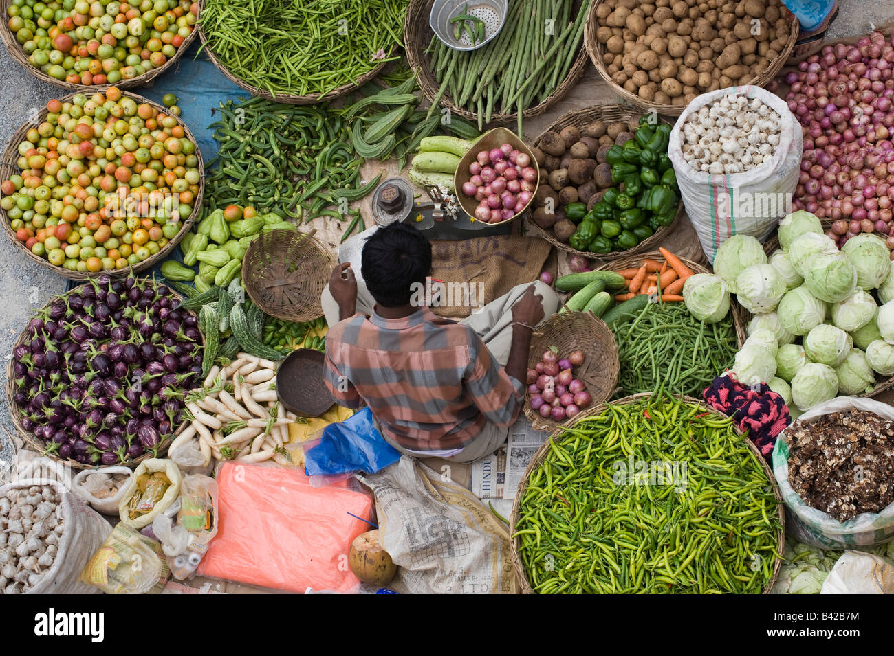 Indian man selling vegetables at a local india market in the town of Puttaparthi, from above. Puttaparthi, Andhra Pradesh, India Stock Photo