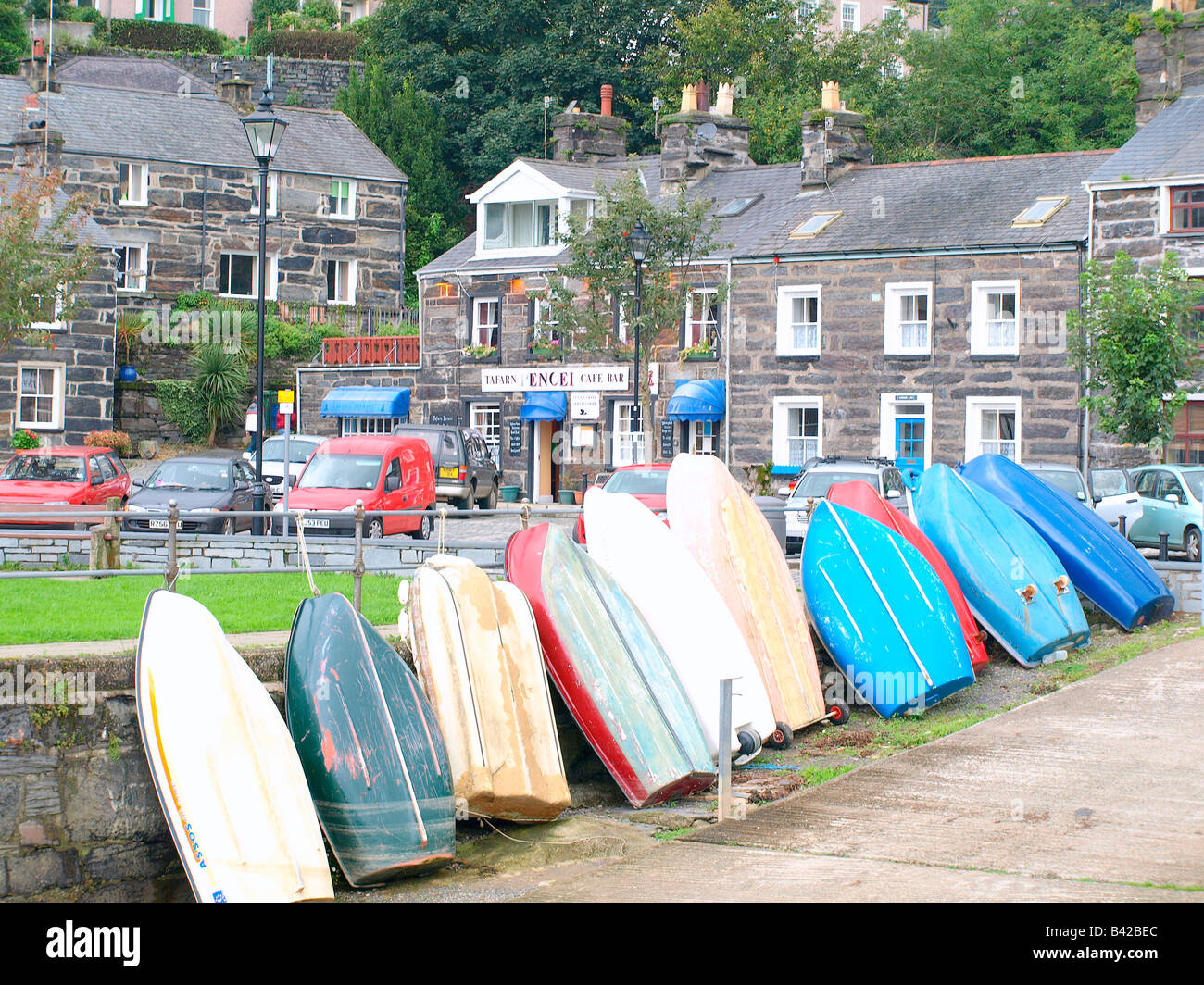 Rowing boats bottom up and gray stone houses and cafe on the harbour at Porthmadog,Wales,uk. Stock Photo