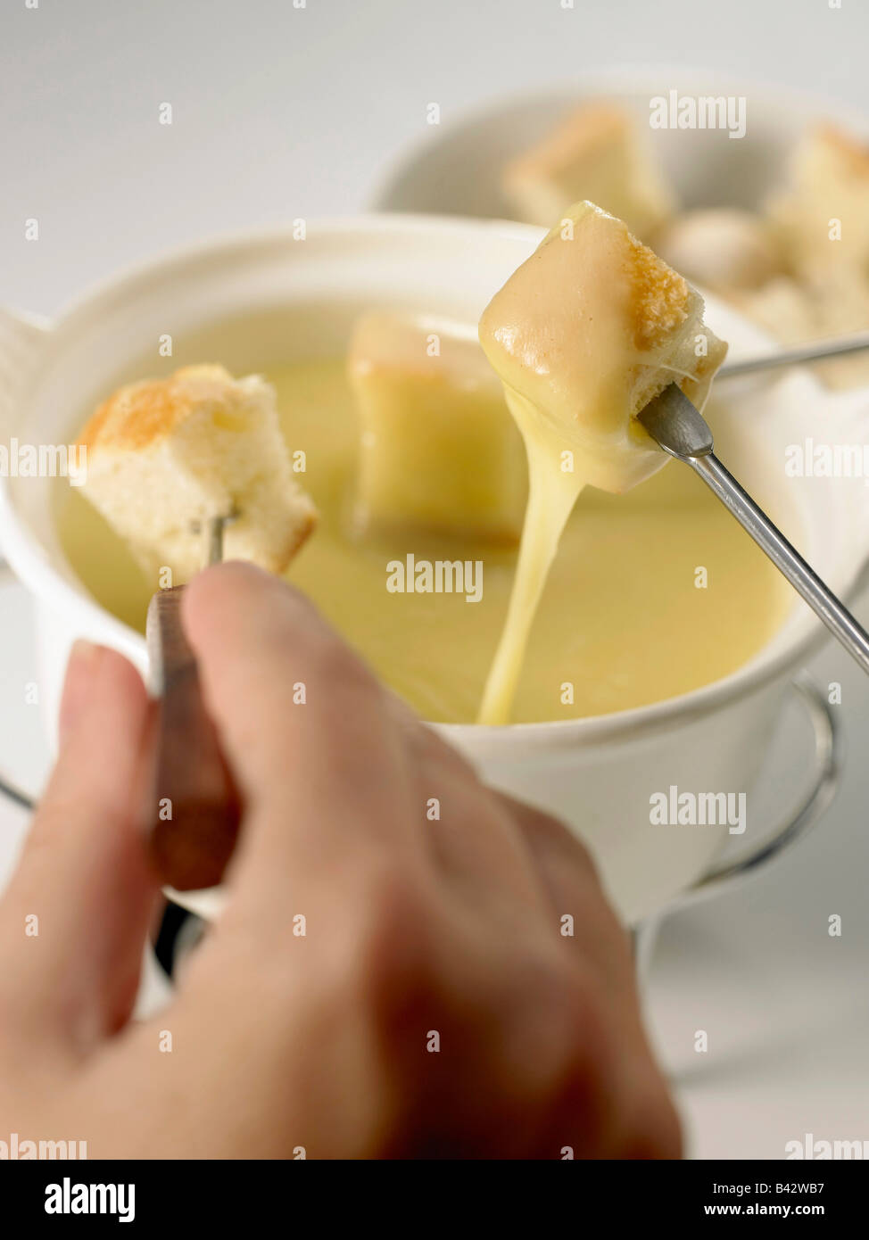 cheese fondue with cubes of bread and hand Stock Photo Alamy