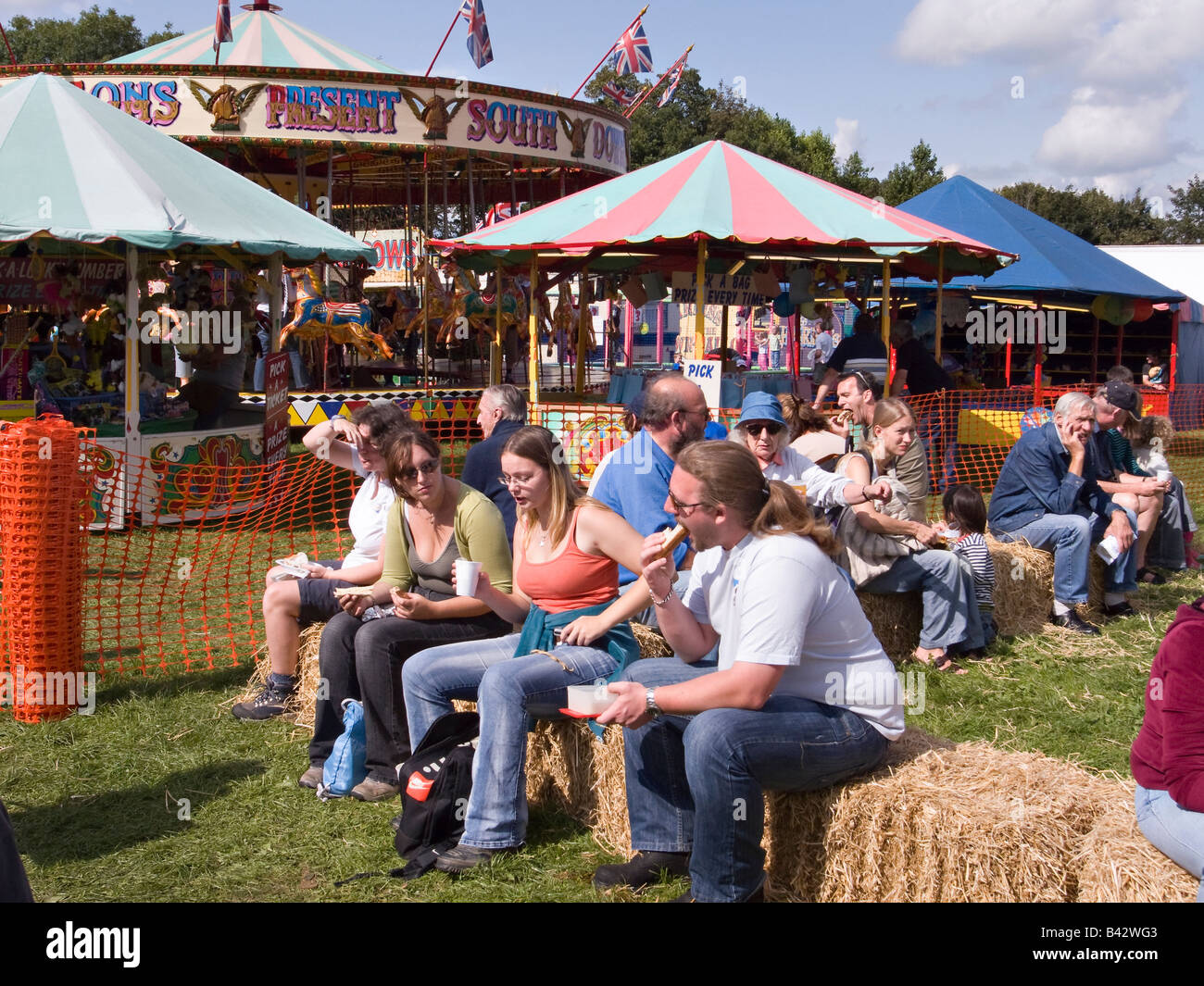 People sitting on hay bales and having refreshments at Findon Sheep Fair, Findon Village, West Sussex, England, UK Stock Photo