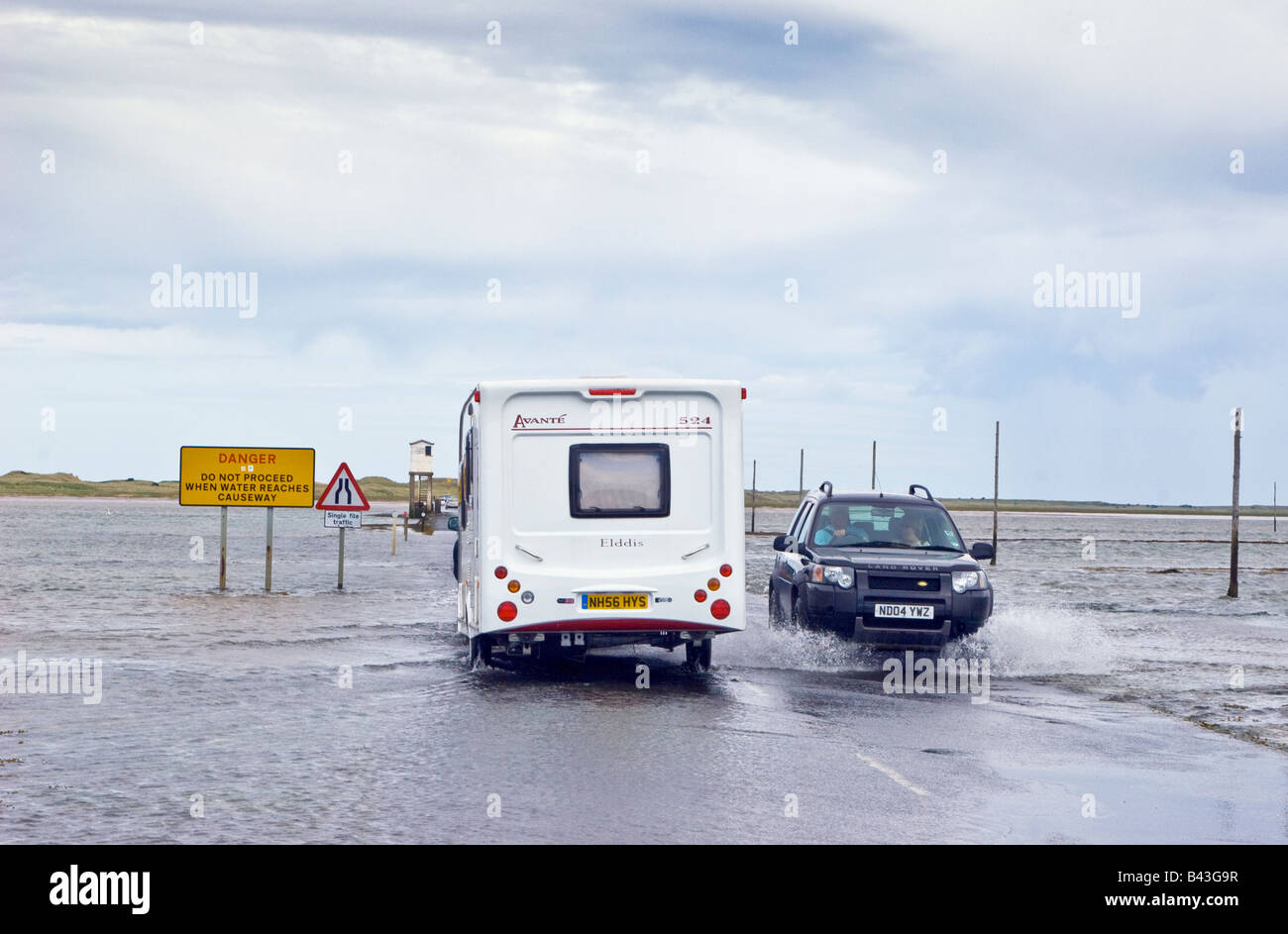 Traffic driving through standing water on a flooded Holy Island causeway Northumberland Great Britain UK 2008 Stock Photo