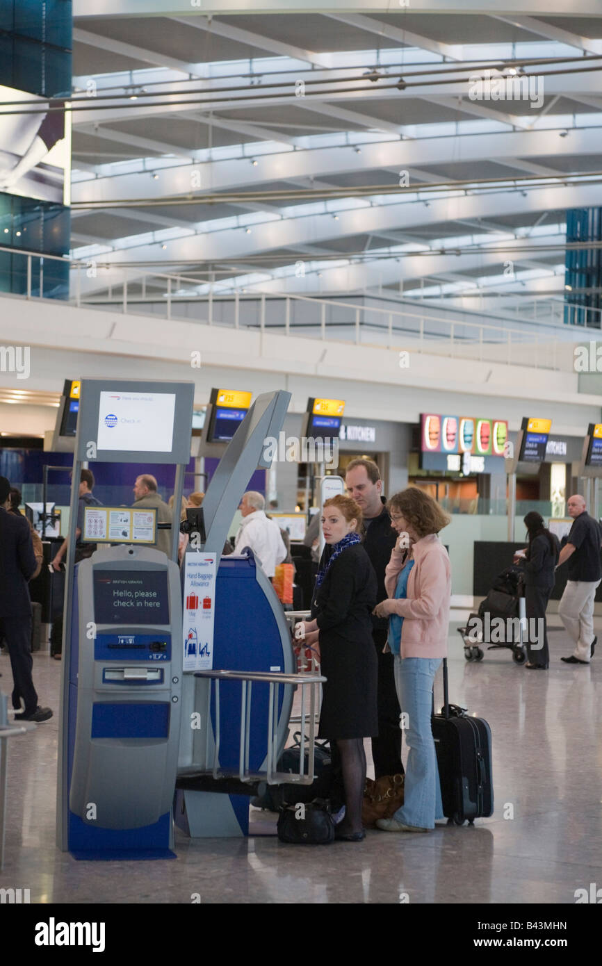 Heathrow London England UK Heathrow Airport passengers using departures check-in kiosk for British Airways in Terminal 5 Stock Photo