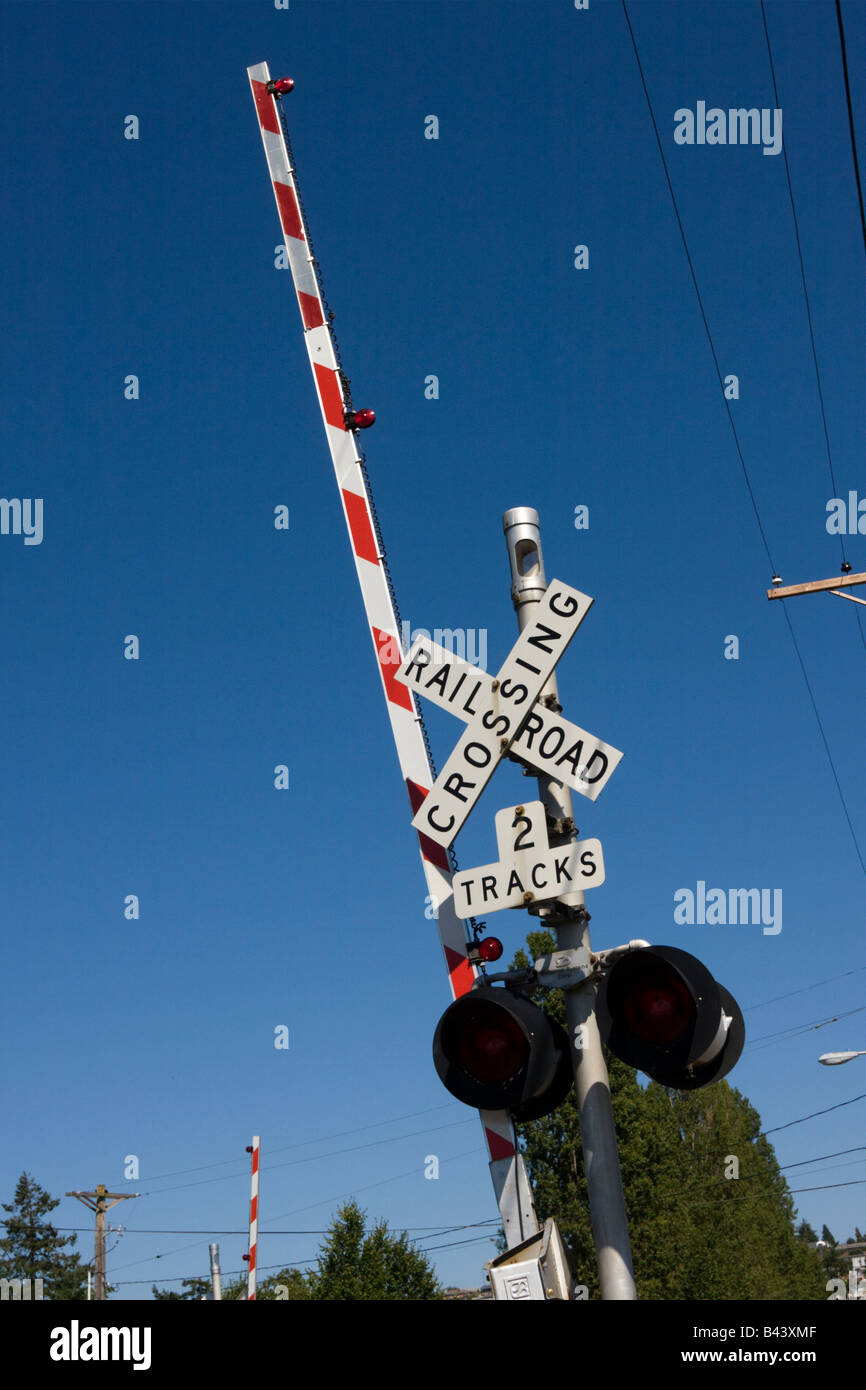 Rail Road crossing barrier up position against blue sky Stock Photo