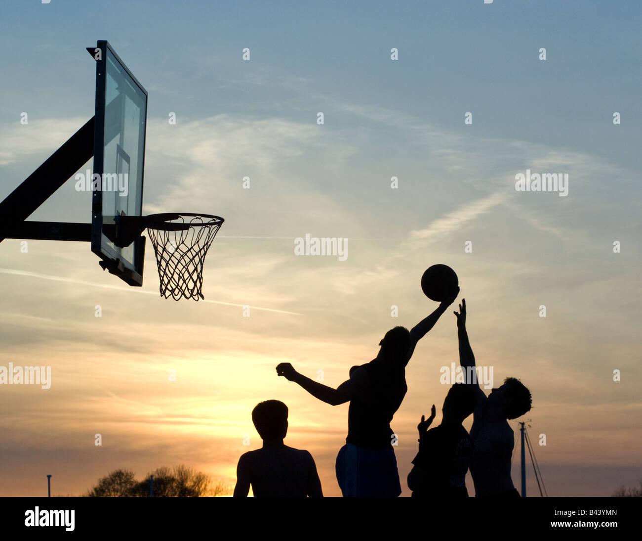 Basketball players shooting basket at sunset in outdoor park, Westport, Ct. Stock Photo