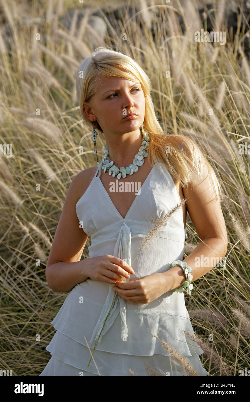 Outdoor Portrait of a Young Blonde Girl in a White Dress in a Field of Grass Stock Photo