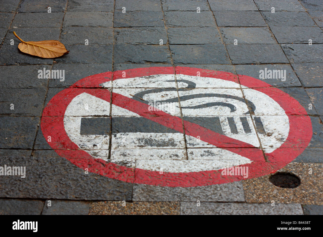 A 'No Smoking' symbol painted on a stone sidewalk. Stock Photo