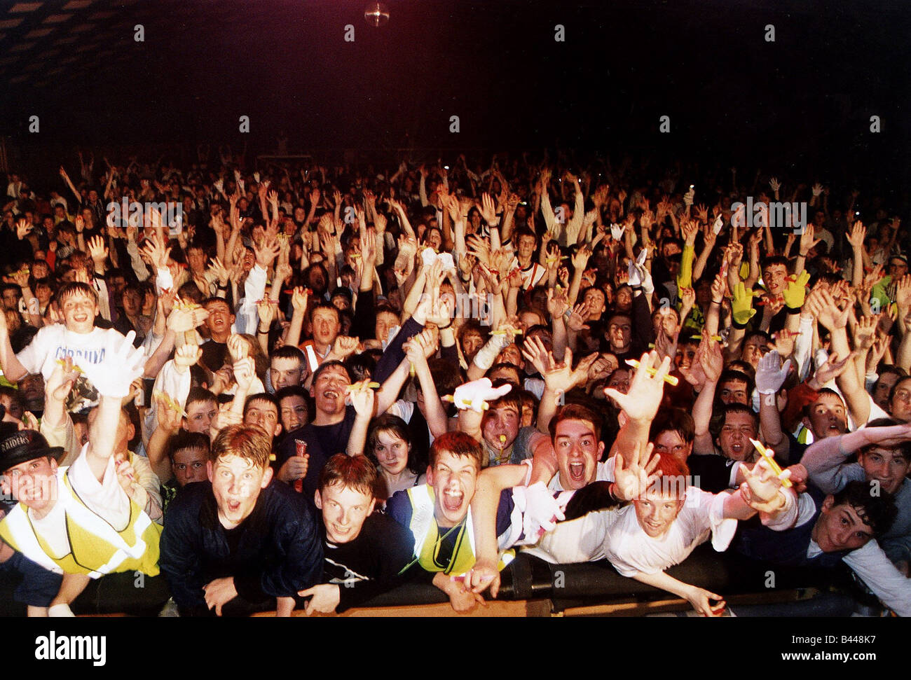 Teenagers at music rave leaning over barrier hands in air Stock Photo ...