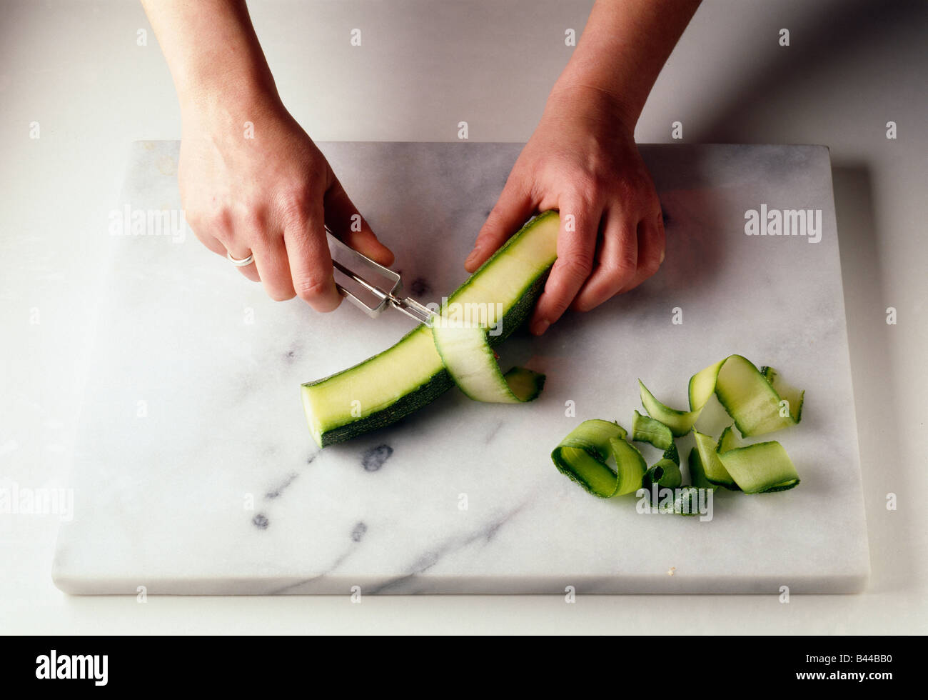 Premium Photo  Peeling fresh green zucchini with peeler. process of  cleaning raw squash with a vegetable peeler.