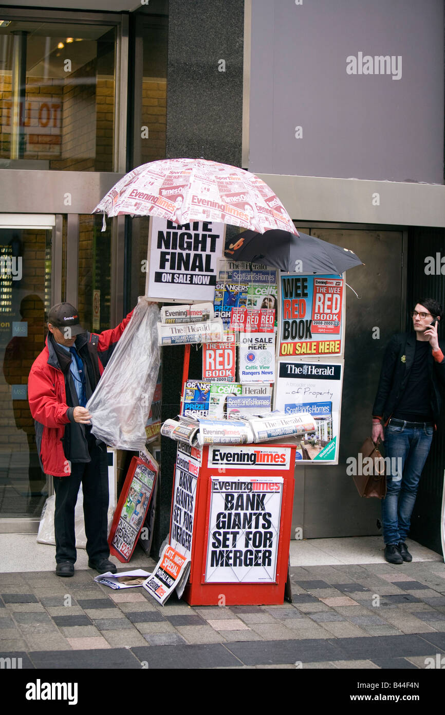 UK Scotland Glasgow Sauchiehall Street news vendors stall under newsprint umbrella Stock Photo