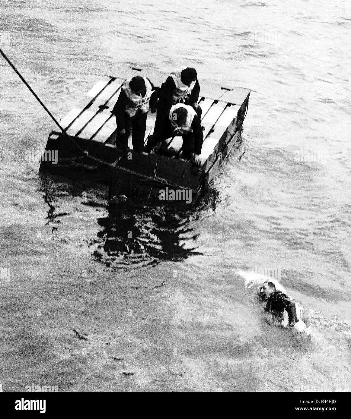 Survivor from sunken merchant ship swims to a life raft and safety WW2 1941 Stock Photo