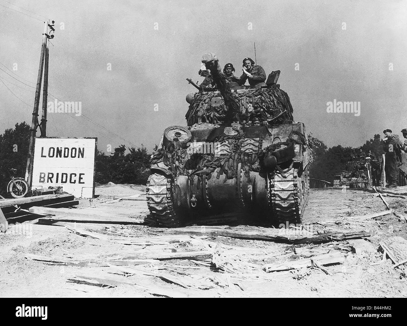 A camouflaged British tank crosses the River Orne at London Bridge in pursuit of retreating Germans during WW2 1944 Stock Photo