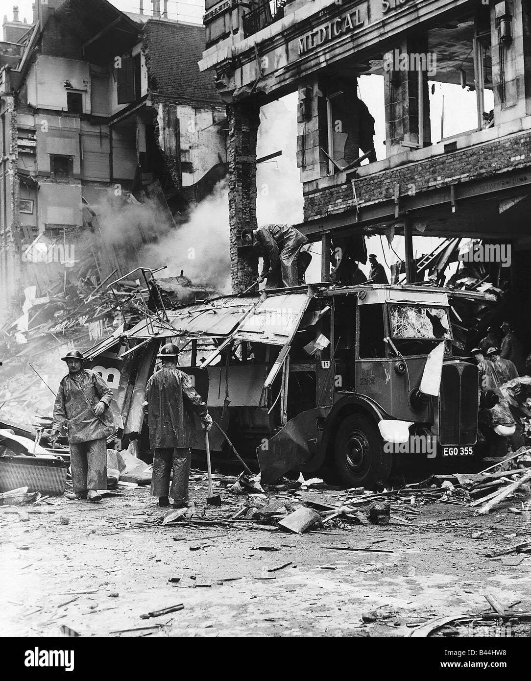 Rescue workers clear a London double decker bus damaged by the blast from a bomb during WW2 air raid 1940 Stock Photo