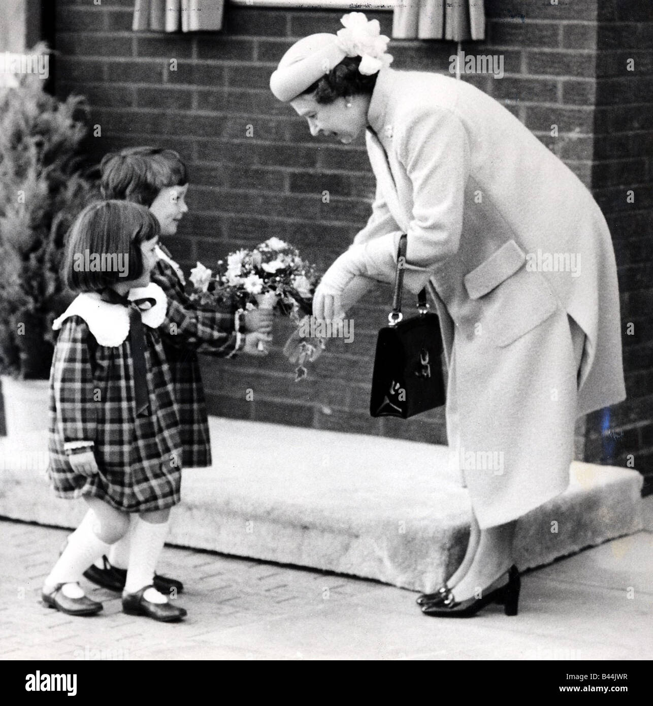 Queen Elizabeth II Four year old twins Sarah and Ruth McLeod giving the Queen flowers in 1986 Stock Photo