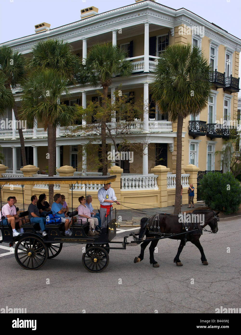 A horse drawn carriage tour passes a stately mansion along the historic