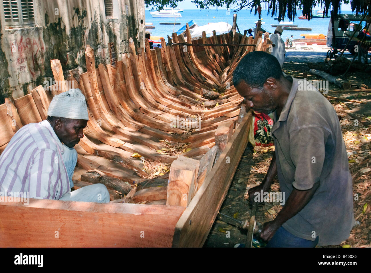 Boatbuilders building a Dhow, a traditional sailboat, Stone Town, Zanzibar, Tanzania Stock Photo