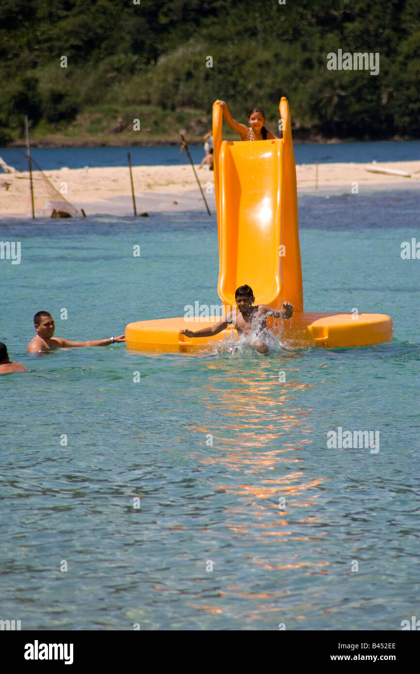 Panama, Isla Grande, Tourists enjoy a sunny day slipping in a floating toboggan in the crystalline waters of the Panamanian Stock Photo